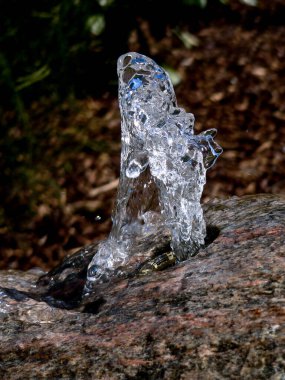 Su damlacıkları / su birikintisi ve güneş ışığı yansımaları. Güneşin altındaki bir derede küçük su damlalarındaki renklerin muhteşem oyunu. Yakından çekilen gün ışığında kıyıda.