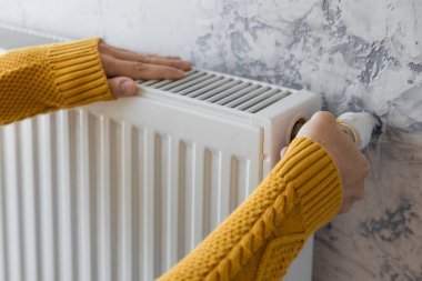 Man adjusting heating radiator or heater to install comfort temperature for energy efficiency and economy in winter. Concept of heating season