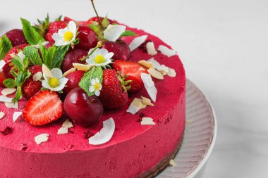 Vegan dessert. Raw berry cashew cake with fresh strawberries and cherries in a plate. Close up. Healthy diet food
