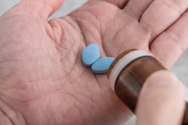 Man takes blue pills in hand. Medicine concept of medication for erection, treatment of erectile dysfunction. Men health. Close up