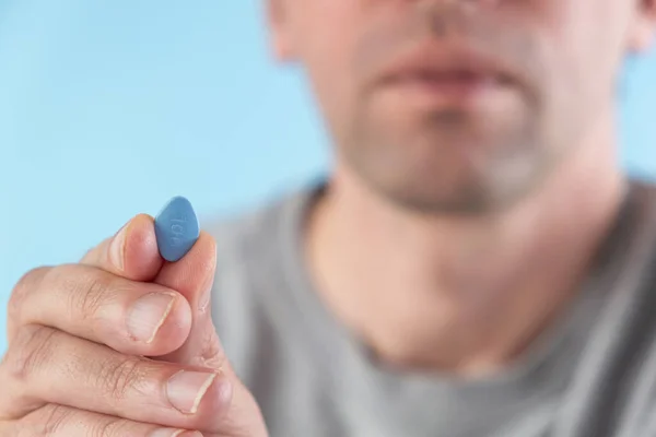Hombre Sostiene Píldora Azul Los Dedos Sobre Fondo Azul Medicina — Foto de Stock