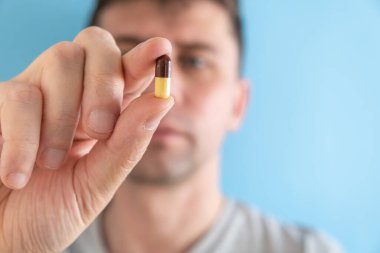 Gastrit, mide ülseri, mide yanması ilacı ya da mavi arka planda hap alan bir adam. İlaca odaklan. İlaç, sağlık, eczane ve tedavi konsepti almak. Seçici odak