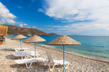 Datca Yarımadası 'ndaki Palamutbuku plajında güneş pansiyonları ve şemsiyeler, Mugla bölgesi, Ege Denizi üzerinde Türkiye. Popüler turist yaz tatili