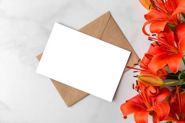 Beyaz arka planda turuncu zambak çiçekleri olan boş bir tebrik kartı. Düğün davetiyesi. Model yap. Düz yatıyordu. Anneler Günü düzeni