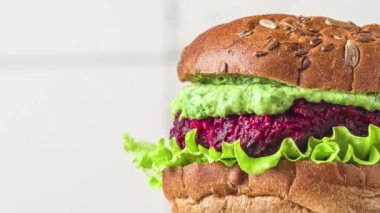 Pancar köklü vegan burger, avokado sosu ve beyaz arka planda marul salatası. Sağlıklı vejetaryen gıda konsepti