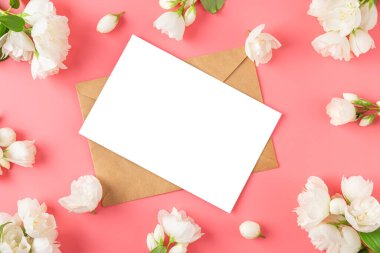 Beyaz yasemin çiçeklerinden yapılmış çerçevedeki boş tebrik kartı pembe arka planda. Düğün davetiyesi. Model yap. Düz yatıyordu. Anneler Günü düzeni