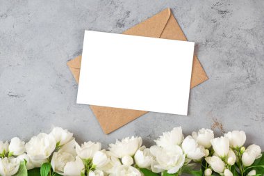 Üzerinde beyaz yasemin çiçekleri olan boş bir tebrik kartı. Düğün davetiyesi. Model yap. Düz yatıyordu. Anneler Günü düzeni