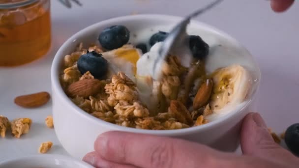 Mannelijke Hand Mengen Griekse Yoghurt Met Haver Granola Banaan Bosbessen — Stockvideo