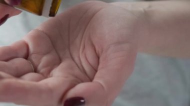 Ağrı kesici beyaz haplar alan bir kadın ya da ilaç şişesinden çıkan tabletlere antibiyotik koyan bir kadın. İlaç, sağlık, eczane ve tedavi konsepti almak. Kapat.