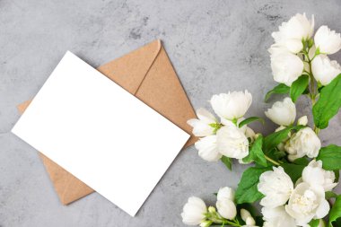 Üzerinde beyaz yasemin çiçekleri olan boş bir tebrik kartı. Düğün davetiyesi. Model yap. Düz yatıyordu. Anneler Günü düzeni