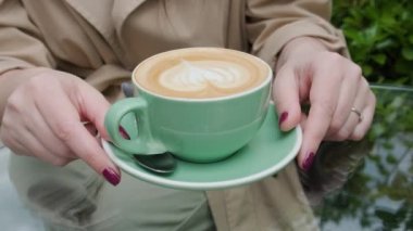 Bir fincan kahve kapuçino ya da kadın kahvesinde latte, açık havada kahve ya da kafede. Klasik kalp şeklinde köpüklü latte sanatı. Lezzetli sıcak içecek.