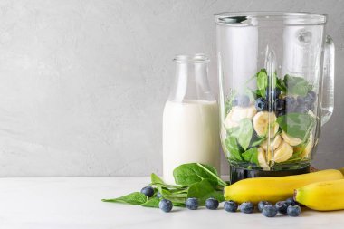 Yabanmersini, muz ve ıspanak karışımı ve yabanmersini ve muzlu milkshake pişirmek için süt şişesi. Vejetaryen içeceği