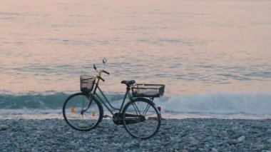 Gün batımında deniz kıyısında bisiklet. Bisiklet okyanusun kıyısında sahilde duruyor. Minimum yaz gün batımı deniz manzarası. Doğa arkaplanı