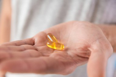 Omega 3 'lü balık yağı kapsülleri, erkek elinde D vitamini. Besleyici destek, ilaç, sağlık için ilaç. Sağlık desteği ve tedavi konsepti. Kapat.