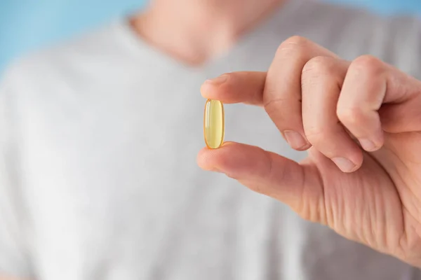 stock image Man holding capsules with omega 3, vitamin D in hand. Nutritional supplement with fish oil. Health support and treatment concept. Close up