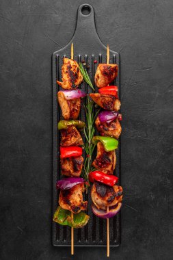 Biber ve soğan dilimli tavuk şişleri. Şiş kebap, siyah arka planda ızgara et. Üst Manzara. dikey yönelim. Lezzetli yemek.