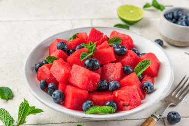Yaban mersinli karpuz salatası ve beyaz masada nane şekeri. Kapat. Sağlıklı yaz vejetaryen tatlısı