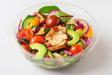 Pakette avokado, domates ve nar bulunan sağlıklı tavuk salatası ya da yiyecek teslimatı. Kapat.