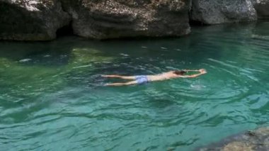 Karadağ 'da nehir akışında kristal berrak mavi suyla yüzen ve sıcak yaz günlerinde dinlenen bir adam. Kafkas erkek soğuk su nehrinin kıyısında yüzüyor. Boş zaman, rahatlama konsepti