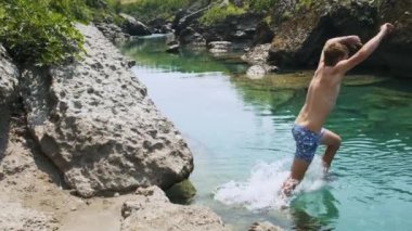 Sıcak yaz günlerinde dinlenmek için Karadağ 'daki Cijevna kanyonuna atlayan bir adam. Beyaz erkek, yüzmek ve eğlenmek için soğuk nehir suyuna dalıyor. Aktif boş zaman