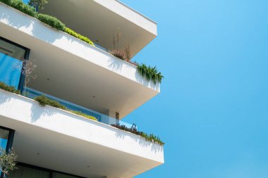 Balkonunda yeşil bitkiler olan modern apartman binasının dış yüzeyini kapatın. Modern sürdürülebilir mimari. Asgari soyut arkaplan