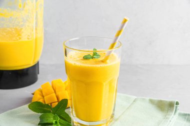 Sağlıklı yaz içeceği yapmak için taze meyve suyu ve blender ile bir bardak sarı mango smoothie. Yemek pişirme konsepti