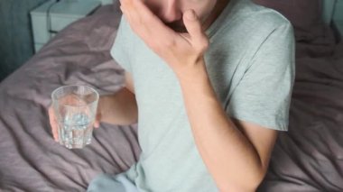 Beslenme takviyeleri. Adam yatakta otururken bir bardak suyla Omega 3 kapsülü içiyor. Sabah dozunda D vitamini. Haplı balık yağı. Sağlık hizmeti kavramı