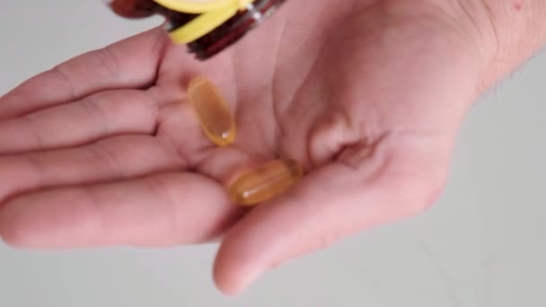 男人向鱼油胶囊中倒入欧米茄3 从药瓶中取出维生素D 营养补充剂 保健支助和治疗概念 靠近点 — 图库视频影像