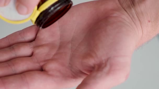 薬瓶から男性の手でコラーゲンで白いカプセルを注ぐ男 栄養補助食品 関節保護 スキンケア 関節炎予防のための薬 ヘルスサポートと治療 — ストック動画