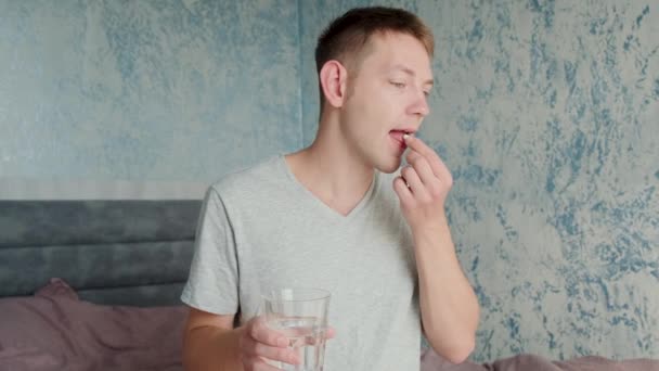 Muž Pije Bílou Tobolku Kolagenem Sklenicí Vody Zatímco Sedí Posteli — Stock video