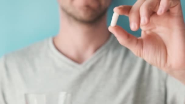 男人拿着用胶原蛋白做的白色胶囊 喝着蓝色底色的杯子水 营养补充剂 关节保护药物 皮肤护理 关节炎预防 有选择的重点 — 图库视频影像