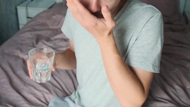 营养补充剂 男人坐在床上喝欧米加3胶囊和一杯水 早上服用维生素D 保健概念 — 图库视频影像