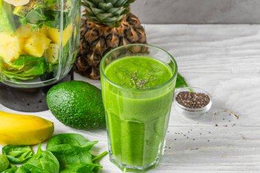 Sağlıklı detoks içeceği yapmak için taze meyve, ıspanak, avokado, chia tohumu ve blender ile bir bardak yeşil smoothie. Yemek pişirme konsepti.