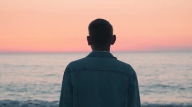 Gün batımında deniz kıyısında tek başına duran adam. Okyanusun kıyısında zihinsel sorunları olan bir erkek. Yalnızlık, depresyon, melankoli, stres konsepti
