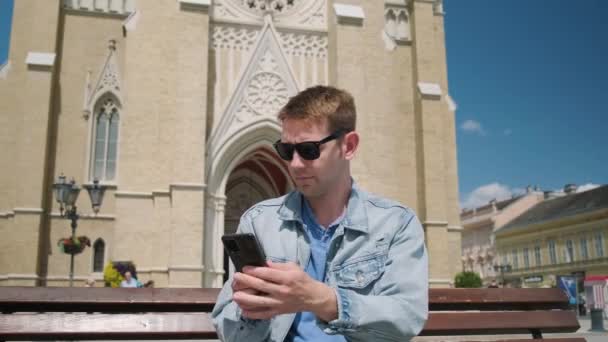 Ein Tourist Sitzt Mit Karte Und Handy Auf Einer Bank — Stockvideo