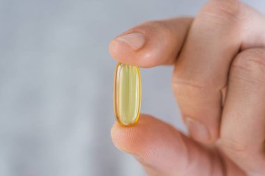 Elinde D vitamini olan kapsüllü bir adam. Balık yağı ile besin takviyesi. Sağlık desteği ve tedavi kavramı.