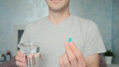 Bir bardak suyla PrEP mavi hapı içen bir adam. Maruz kalma öncesi korunma ilacı kullanılarak HIV önleme. Erkek sağlığı. AIDS önleme kavramı.