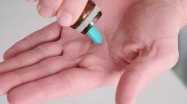 Adamın biri elinde ilaç şişesinden PrEP mavi hap döküyor. Maruz kalma öncesi korunma ilacı kullanılarak HIV önleme. Erkek sağlığı. AIDS önleme kavramı.