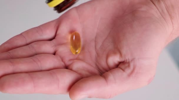 男人向鱼油胶囊中倒入欧米茄3 从药瓶中取出维生素D 营养补充剂 保健支助和治疗概念 靠近点 — 图库视频影像