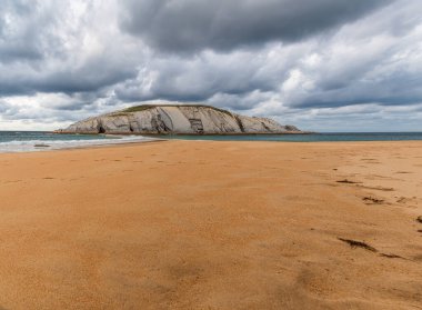 Ada del Castro 'nun panoramik manzarası kumlu Covachos plajı, Santander, Cantabria, İspanya. Karamsar bulutlu günde Rocky Adası ve kumlu tükürük. Tatillerde popüler seyahat