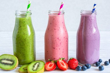 Taze meyve suyu çeşitleri ya da cam şişelerde taze böğürtlenli milkshake ve beyaz ahşap arka planda saman. Sağlıklı bir diyet içeceği. Metin için boşluk