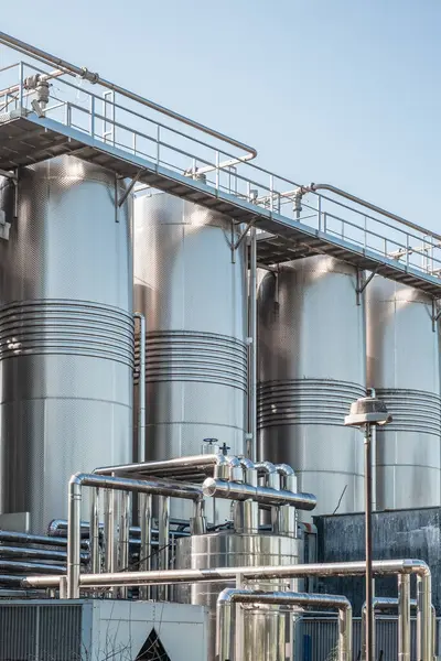 Stainless group vertical steel storage tanks for wine fermentation and maturation in modern winery factory production. Industrial and technology background. Vertical orientation.