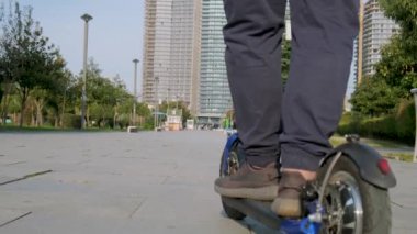 Şehirde e-scooter kullanan iri yarı bir adamın arka görüntüsü. Erkek, dışarıda elektrikli scooter kullanıyor. Elektrik ve ekolojik taşıma. Çevre dostu ulaşım. Sürdürülebilir yaşam tarzı kavramı.