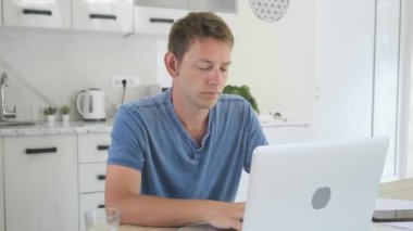 Evde dizüstü bilgisayarla uzun bir gün geçirdikten sonra boynu ağrıyan çok çalışan genç bir iş adamı. Erkek serbest çalışanın bilgisayar üzerinde çalışırken sağlık sorunu var. Ofis sendromu kavramı.