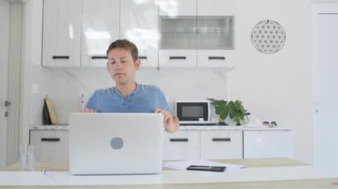 Neşeli genç tüccar dizüstü bilgisayarla çalışırken işten memnun oluyor. Serbest yatırımcı internet işini bitirir ve ev ofisinde dinlenir..