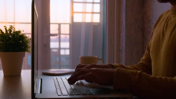 男性のビジネスマンは 夕方には屋外の日没時に自宅からラップトップコンピュータにキーボードを入力します オンラインで働く男 フリーランサーコピーライターの作業プロジェクト テキストを入力し 何かを編集します リモートジョブ — ストック動画