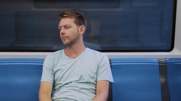 年轻体贴入微的疲倦男子坐在地铁的空车上 在漫长的工作日之后 筋疲力尽的男性在深夜乘地铁回家 生活方式概念 — 图库视频影像