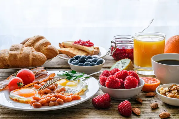 Breakfast buffet. Full english and continental. Large selection of brunch and breakfast food on the table with egg, bacon, toast, orange juice, croissant, coffee, fruits and nuts.