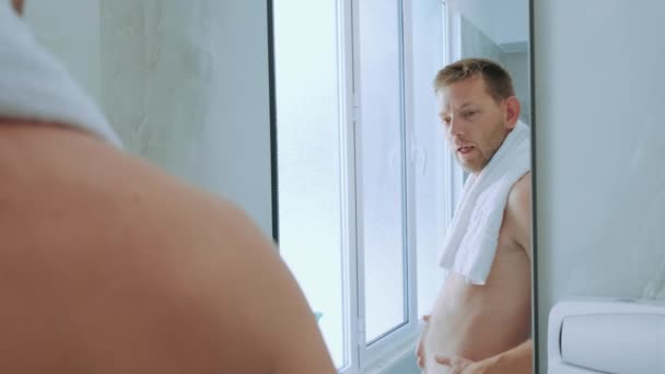 Jonge Tevreden Blanke Man Handdoek Controleert Zijn Lichaamsvorm Spiegel Badkamer — Stockvideo