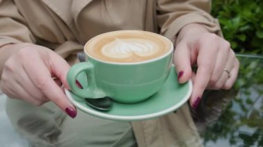 Bir fincan kahve kapuçino ya da kadın kahvesinde latte, açık havada kahve ya da kafede. Klasik kalp şeklinde köpüklü latte sanatı. Lezzetli sıcak içecek.